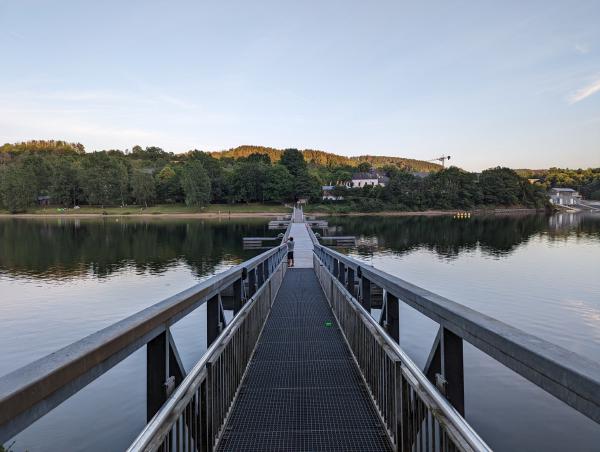 A photo looking directly down a long bridge running just an top of a glassy lake.