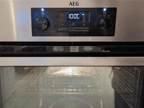 A photo of the covered baking dish in an electric oven reading 100 °C