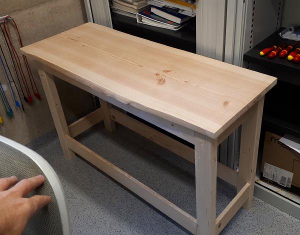 An unfinished timber bench sitting in the corner of a room.