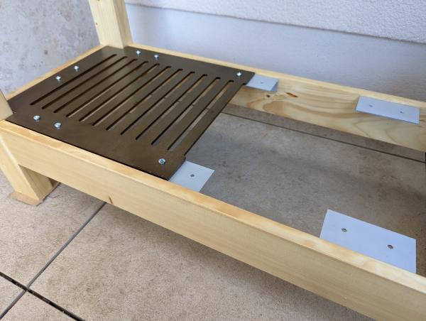 A partially installed shelf built into the bench with steel grates.