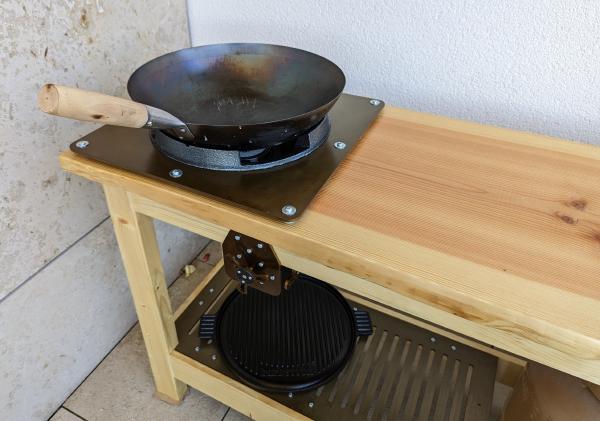 The benchtop and gas burner with a wok on top.