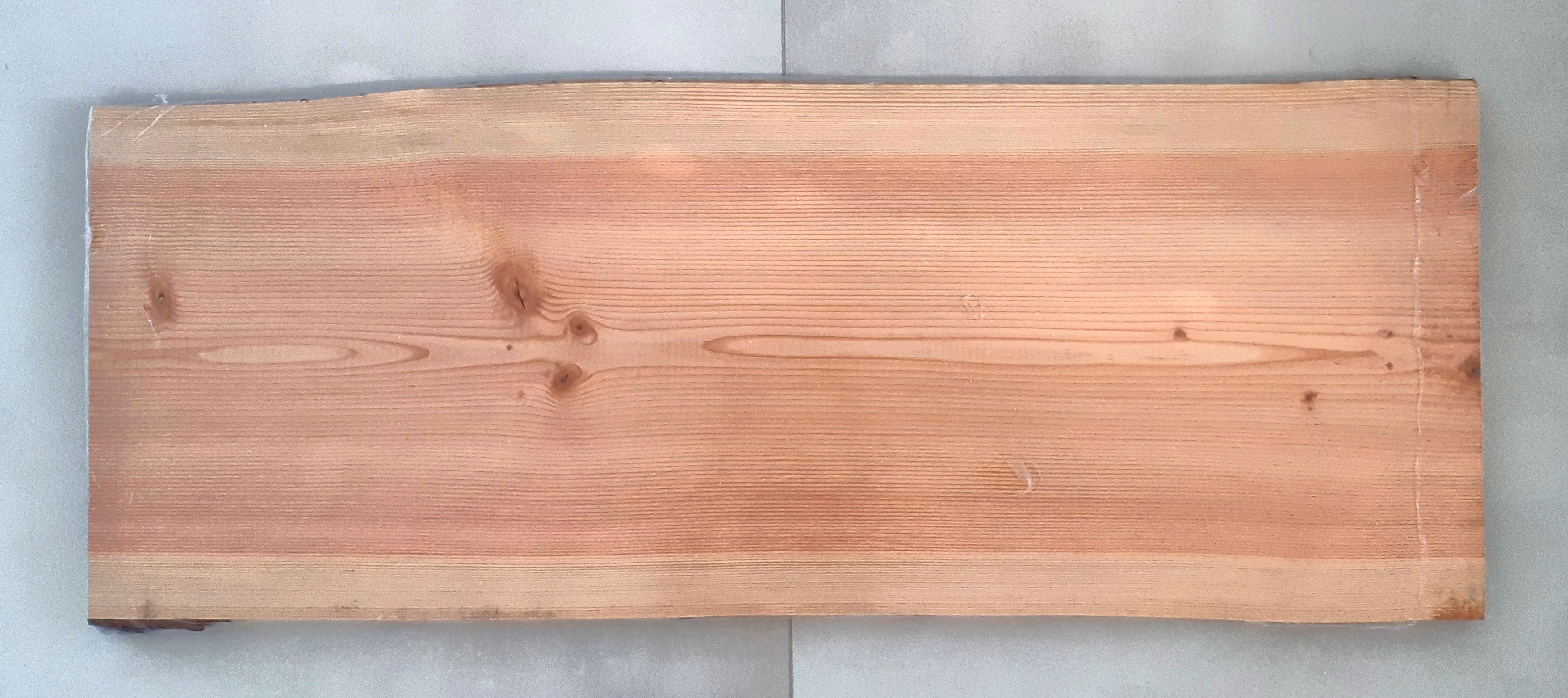 A photo of a timber slab from a Douglas Fir tree laying on grey tiles.