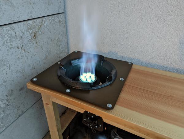 A long exposure photo of the wok burner showing a huge jet-like blue flame coming from the center.