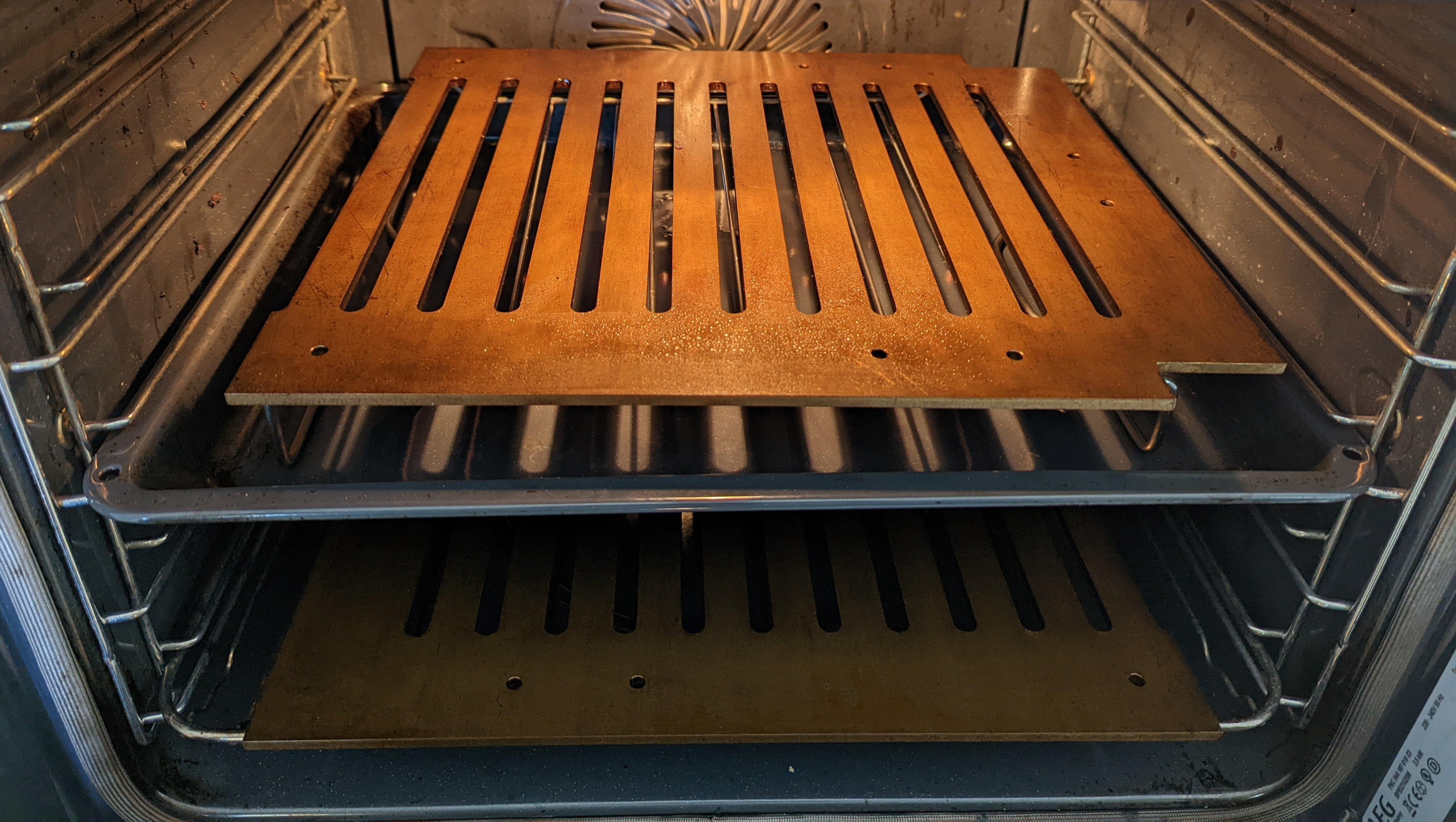 Two brown steel grates sitting on racks in a fan forced oven.