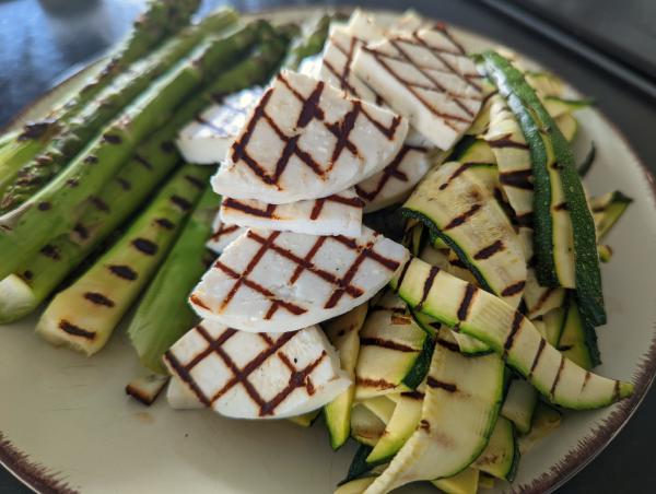 A photo of grilled asparagus, cheese and zucchini showing strong diamond shaped grill marks.