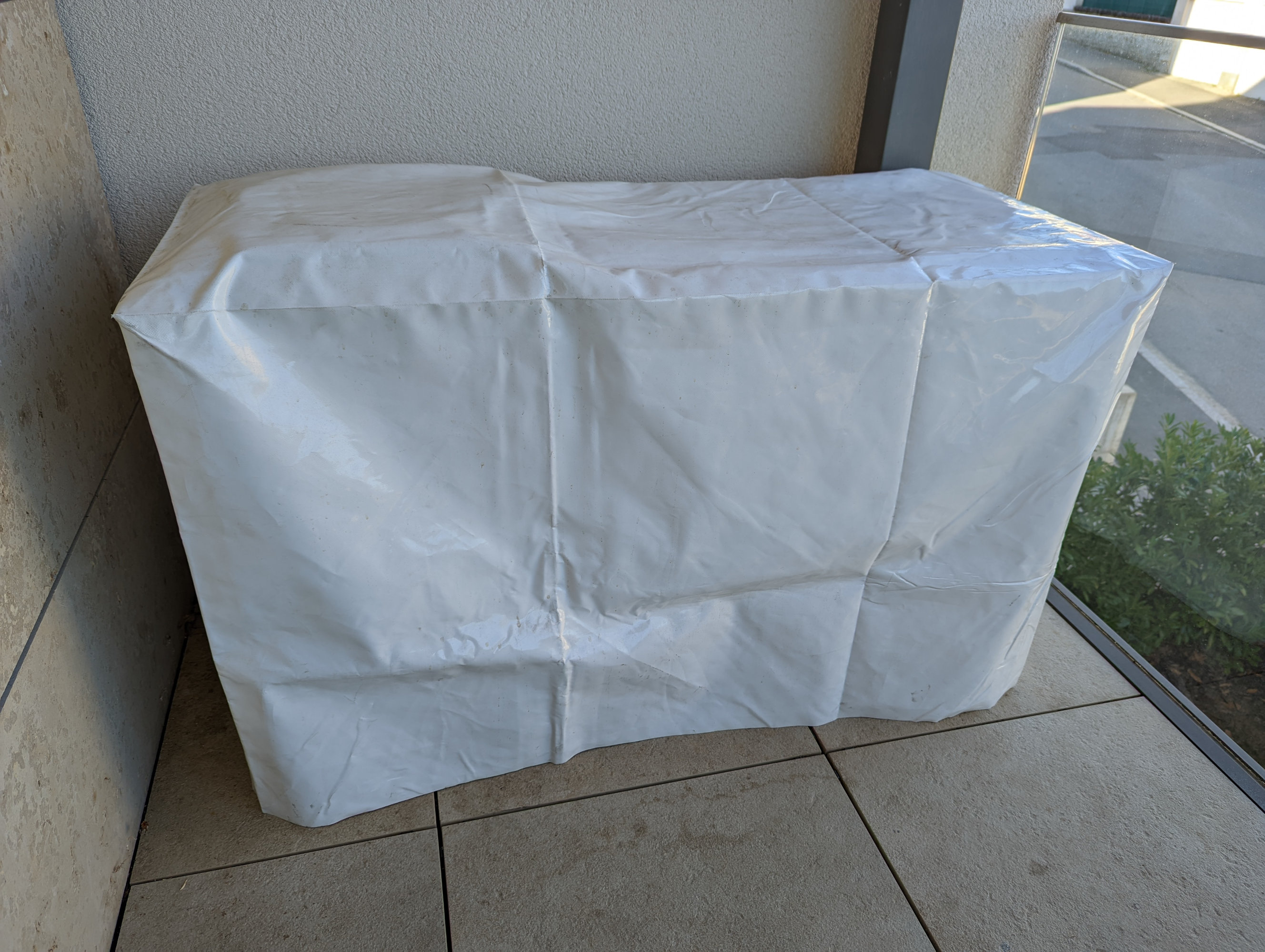 A photo of a white vinyl furniture cover placed over the top of the outdoor cooking station.