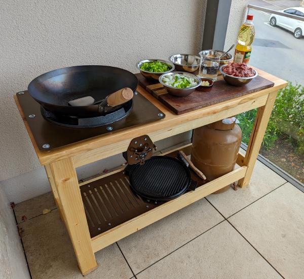 The cooking station with a wooden cutting board containing all of the ingredients for a meat and vegetable stir fry.